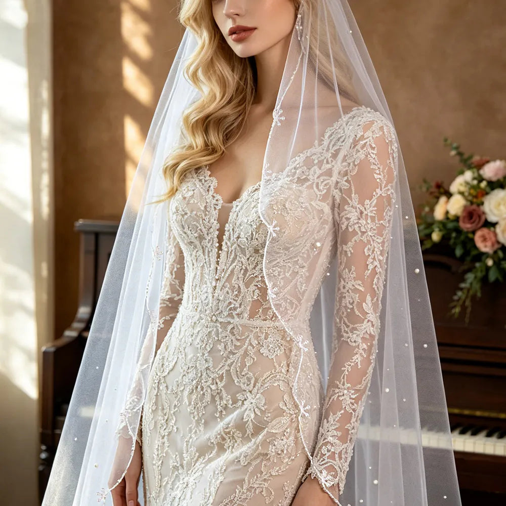 Bride in long-sleeve lace wedding gown styled with sheer 100cm pearl veil draped softly over shoulders