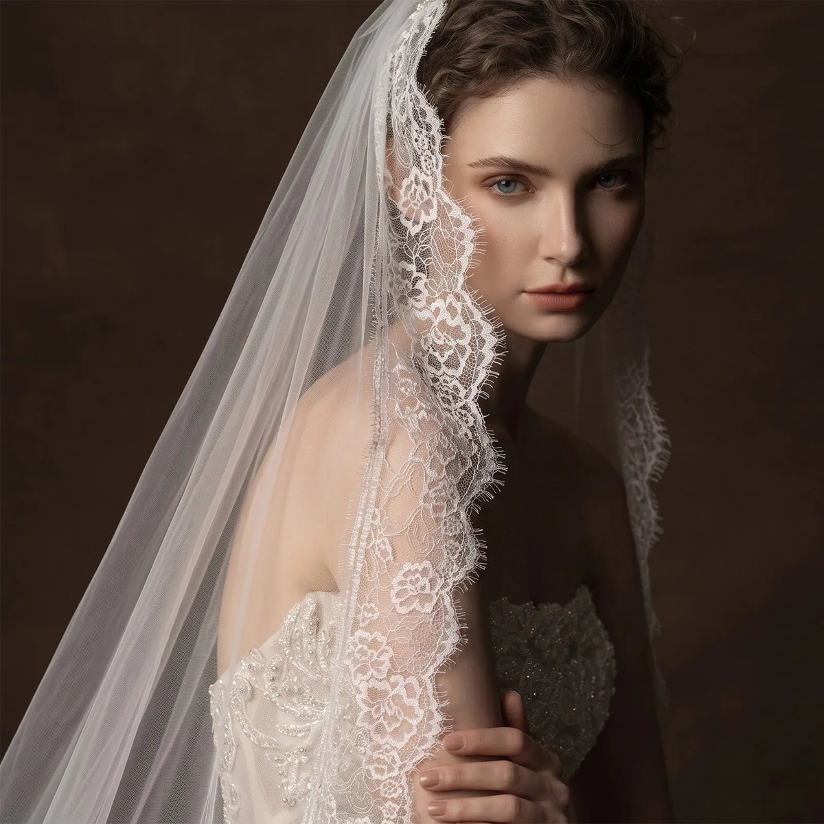 Front portrait of bride in a sleek strapless bridal gown with a single-tier mantilla veil resting on her head and cascading symmetrically over both shoulders