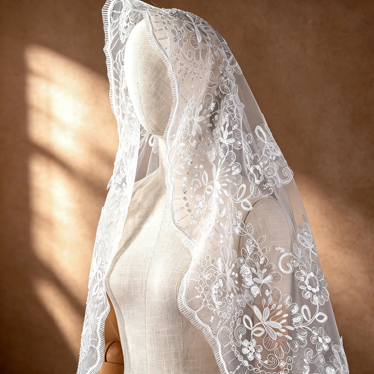 Close-up of sheer blusher veil draped over mannequin head showing intricate sequin floral lace embroidery