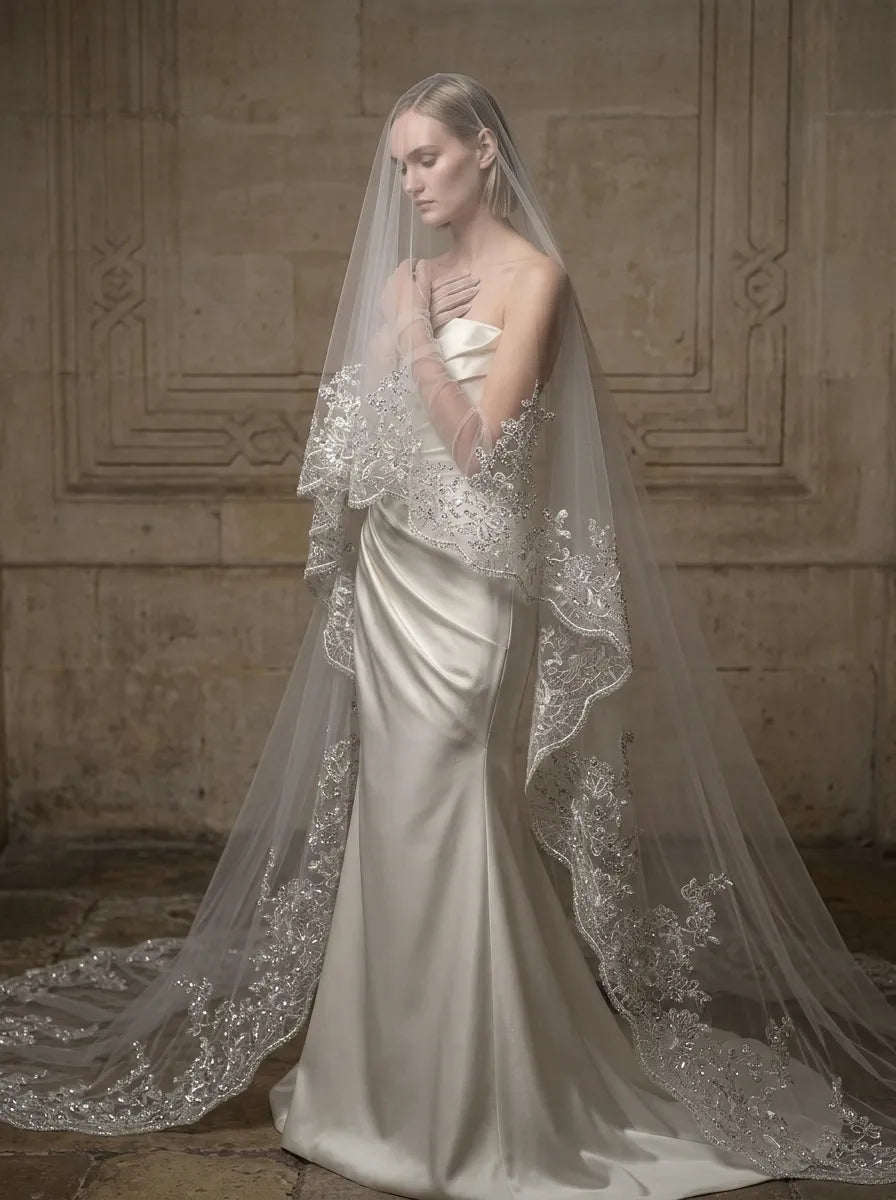Front portrait of bride with sheer blusher veil draped over her face and heavy sequin lace trim framing shoulders