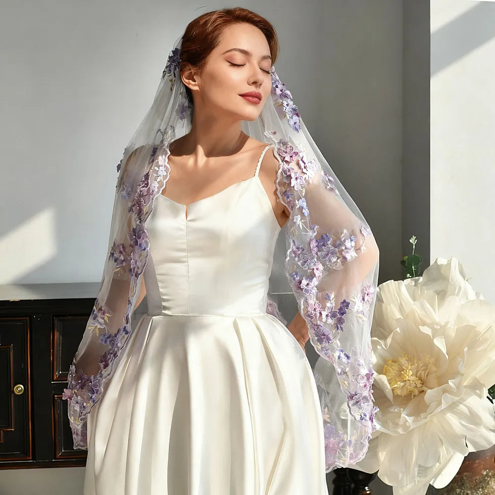Romantic front portrait of bride in ivory satin wedding dress with eyes closed, wearing a 100cm single-tier soft white veil adorned with cascading purple 3D floral lace along shoulders