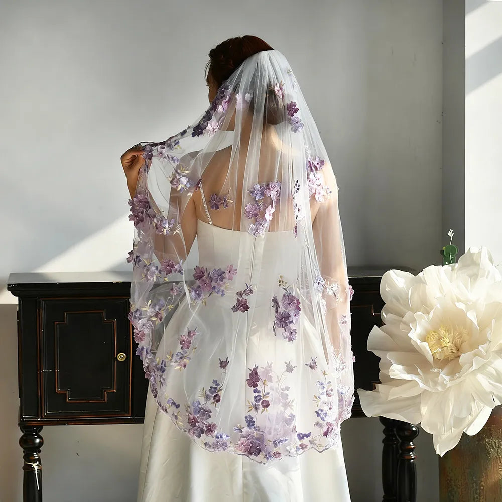 Rear view portrait showing the natural drape of 100cm soft white veil with dense lavender floral appliques near the hem, contrasting gracefully against a plain white bridal dress