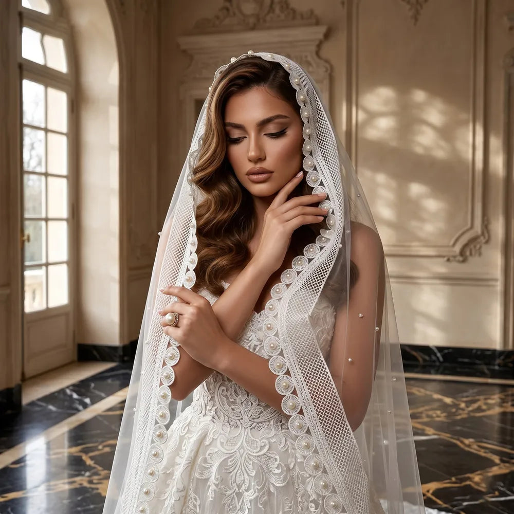 Close-up portrait of blonde bride holding wide scalloped pearl lace edge in front of soft blue backdrop