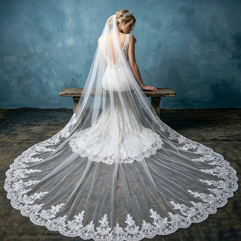 Bride in low-back mermaid gown seated on wooden bench with 300cm cathedral lace veil cascading over the floor