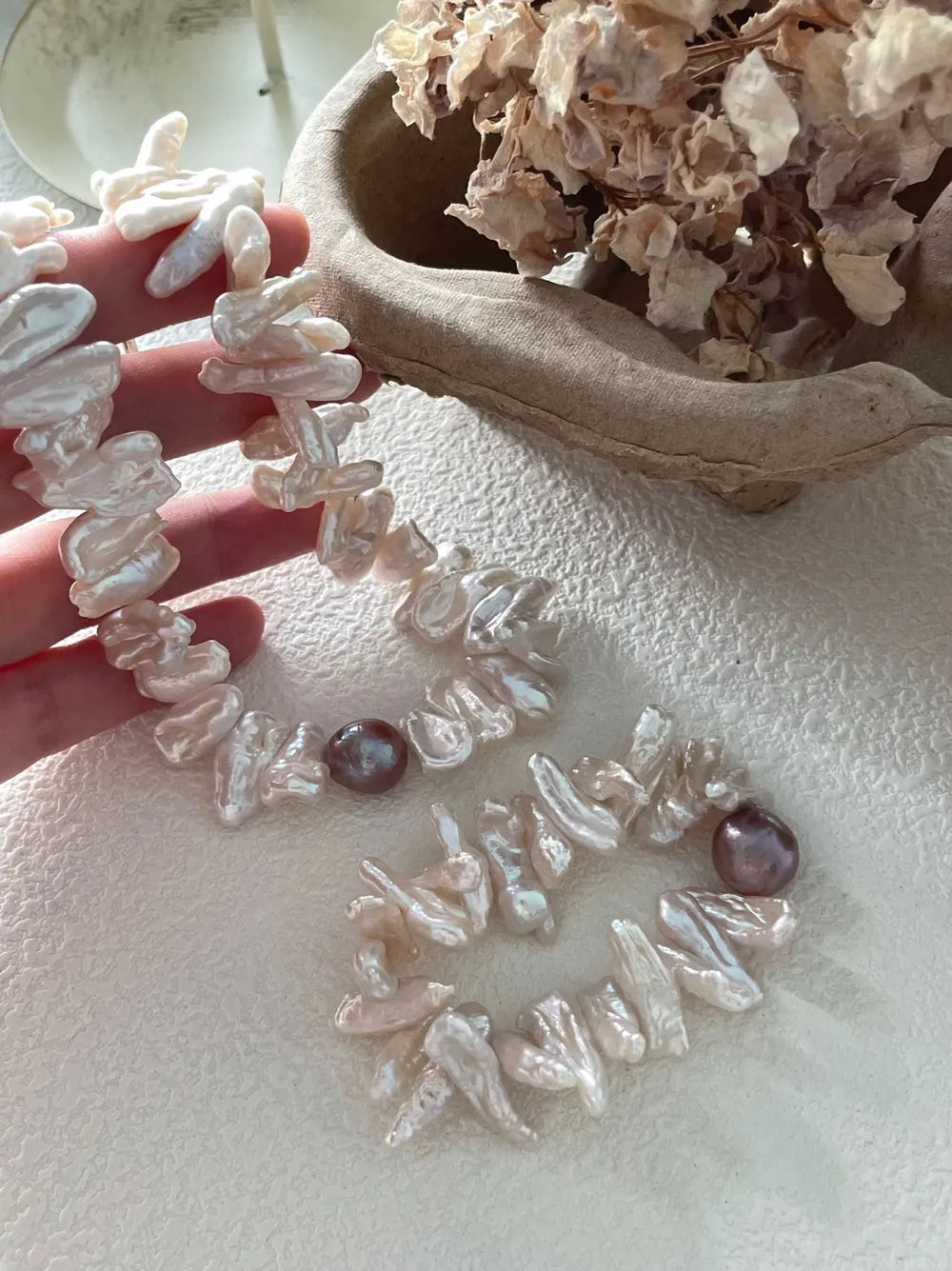 Close-up of model's wrist displaying the stick baroque pearl bracelet with purple accent pearl.