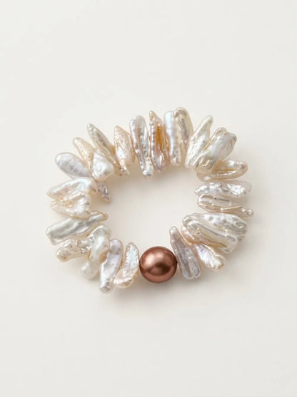 Flatlay view of the circular stick baroque pearl elastic bracelet with a lustrous purple pearl.