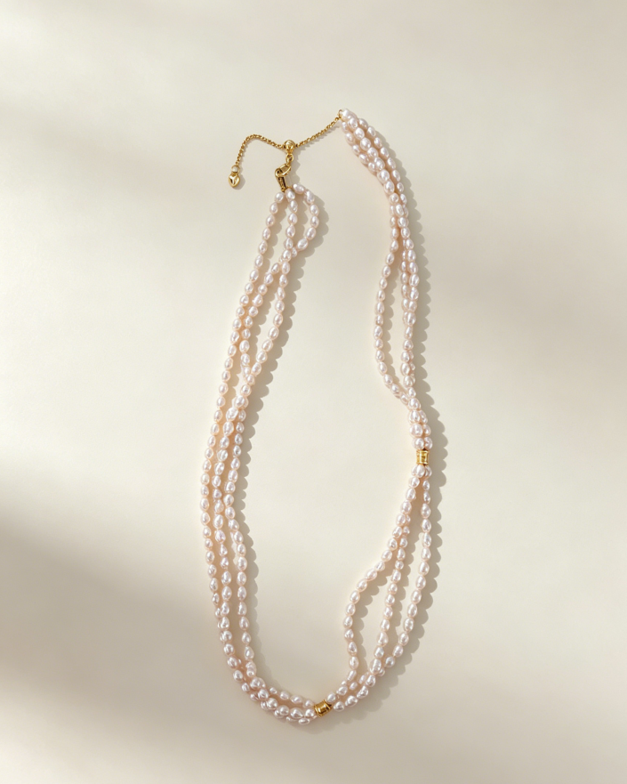 Three delicate strands of freshwater pearls create a softly layered necklace, finished with refined 18K gold-plated silver details.