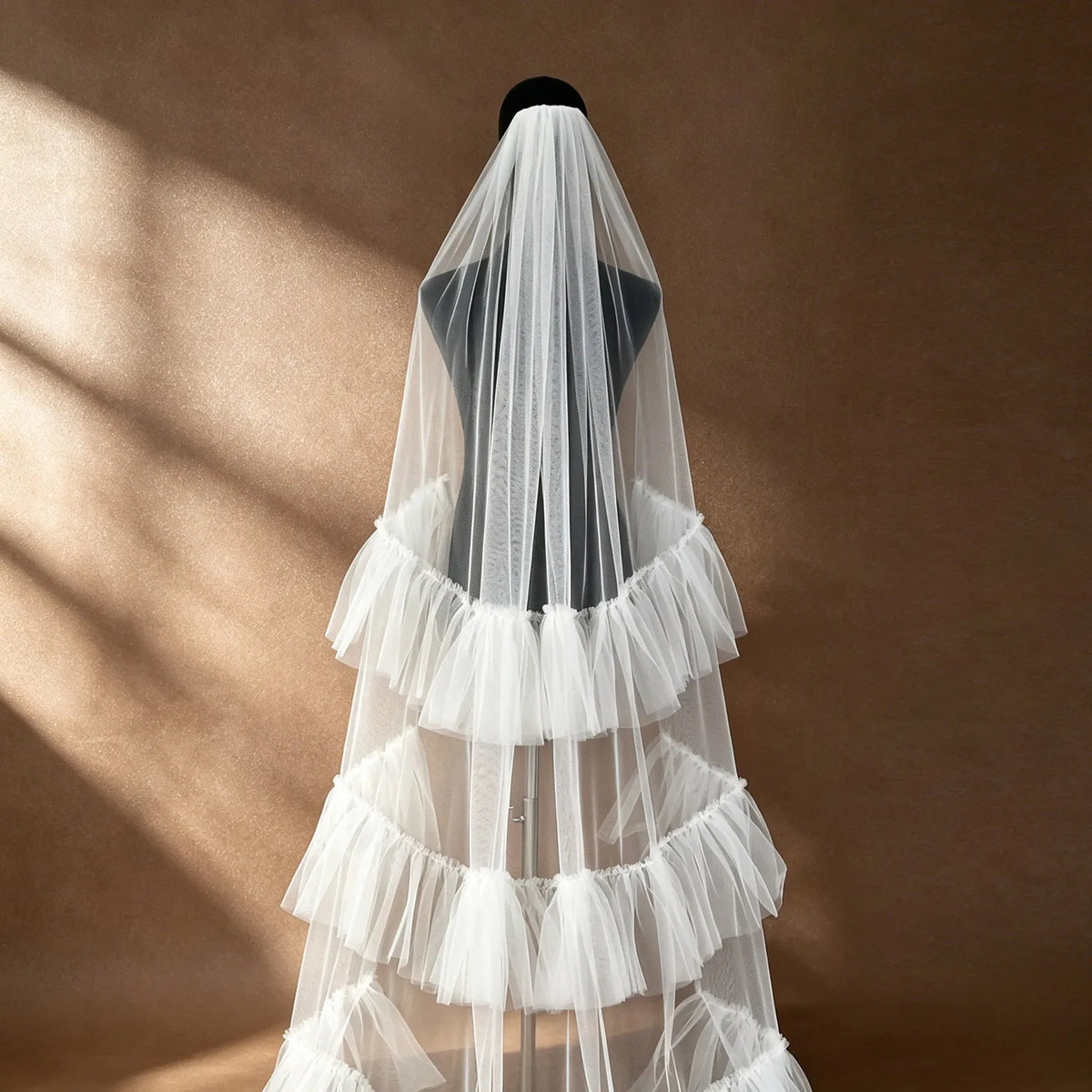 Rear view of 300cm cathedral veil with soft tiered ruffles on a black dress form mannequin