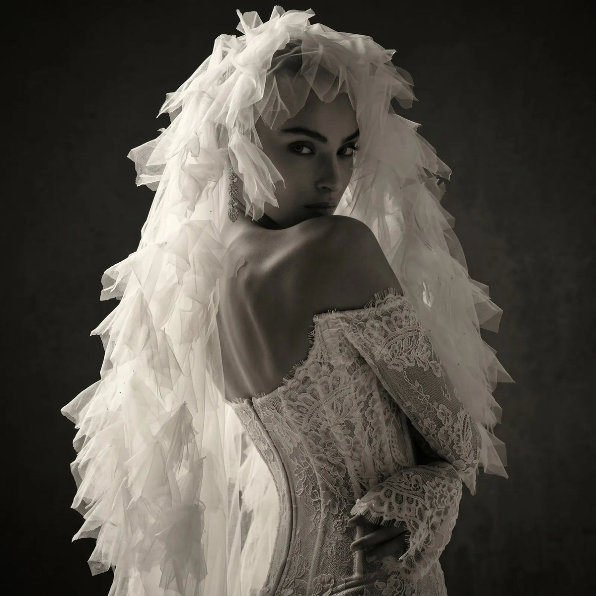 Dramatic black and white studio portrait of bride wrapped in voluminous tulle flounces