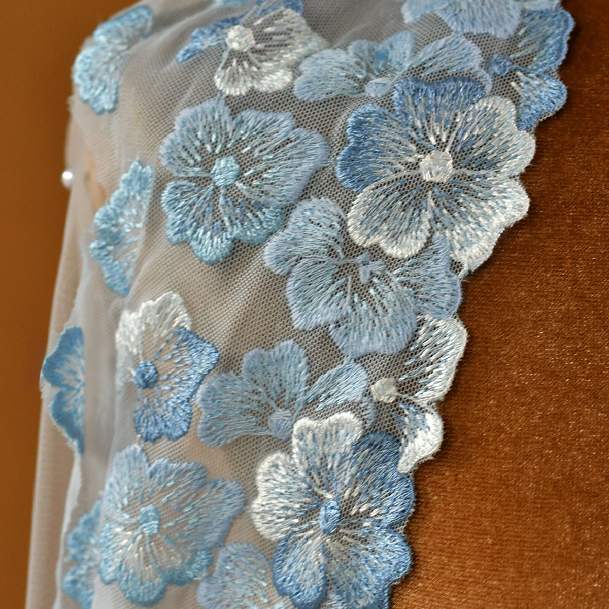 Whimsical romantic single-tier fingertip length bridal veil adorned with blue 3D embroidered floral lace along the edge and scattered lustrous pearl seed accents.