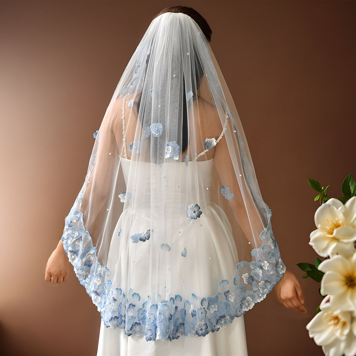 Whimsical romantic single-tier fingertip length bridal veil adorned with blue 3D embroidered floral lace along the edge and scattered lustrous pearl seed accents.