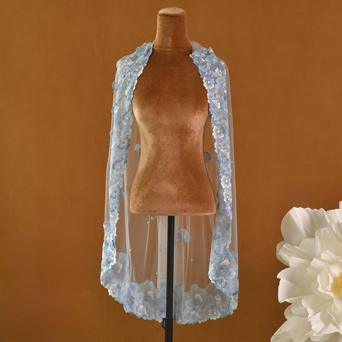 Whimsical romantic single-tier fingertip length bridal veil adorned with blue 3D embroidered floral lace along the edge and scattered lustrous pearl seed accents.