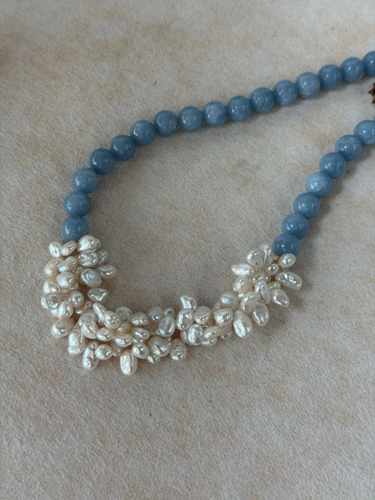 Close-up detail of the intricately hand-woven white baroque pearl petals paired with round blue angelite beads.