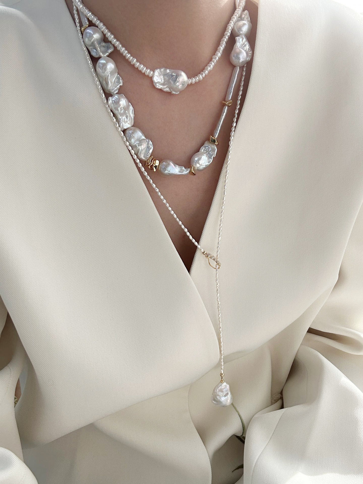 Model wearing the Y-shape Keshi pearl lariat necklace with a deep V-neck white blazer.