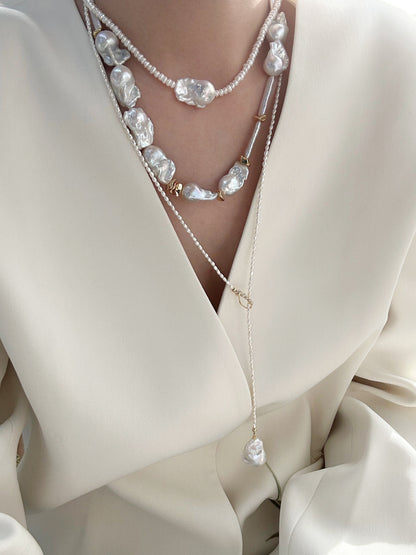 Model wearing the Y-shape Keshi pearl lariat necklace with a deep V-neck white blazer.